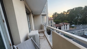 A balcony with a table and chairs, a potted plant, and a view of the street and buildings. - Cozy, air-conditioned 2-bedroom apartment, Toulon (Toulon)