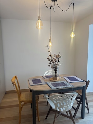 Uma área de refeições com uma mesa redonda, duas cadeiras e luminárias pendentes.