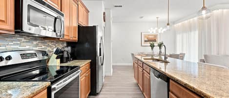 Una cocina moderna con armarios de madera, electrodomésticos de acero inoxidable y encimera de granito.