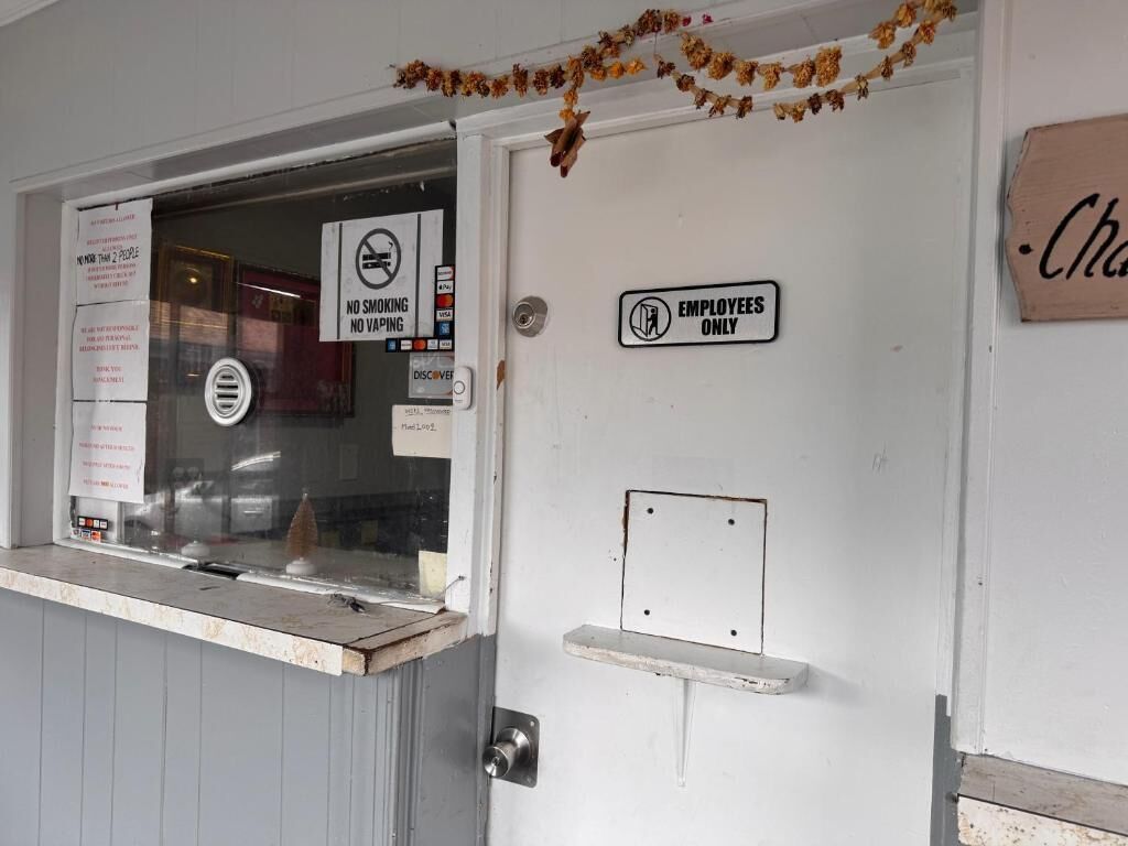 A door with a 'No Smoking' sign, an 'Employees Only' sign, and a small shelf.
