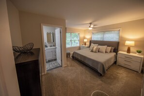 A bedroom with a bed, bedside tables, a nightstand, a ceiling fan, and a window with blinds.