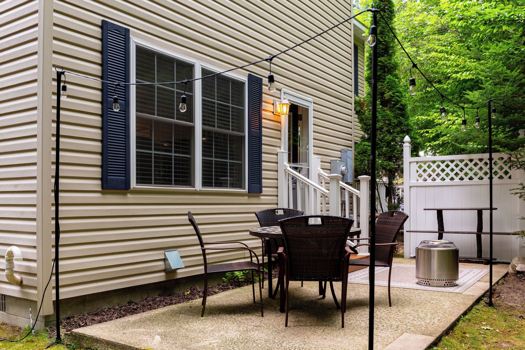 A house with a patio area featuring outdoor furniture and a grill.