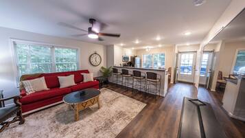 A spacious living area with a red sofa, a coffee table, and a ceiling fan.