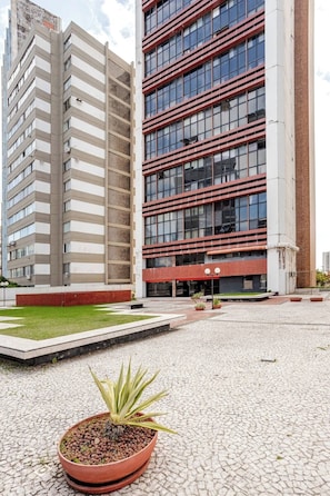 Un bâtiment moderne doté d’une cour intérieure, de plantes en pot et d’un chemin pavé.