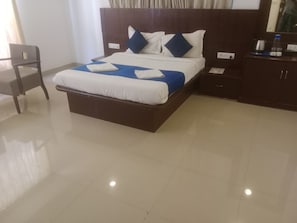 Ein Hotelzimmer mit einem großen Bett, einem Holzkopfteil, einem Nachttisch mit Lampe und einem Sessel.