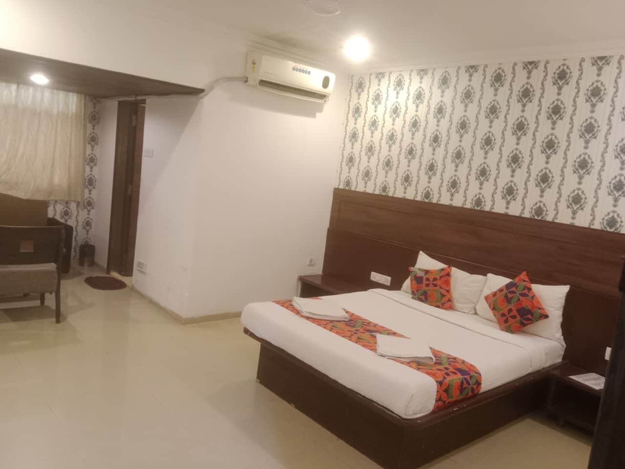 Una habitación de hotel con cama, mesita de noche y aire acondicionado.
