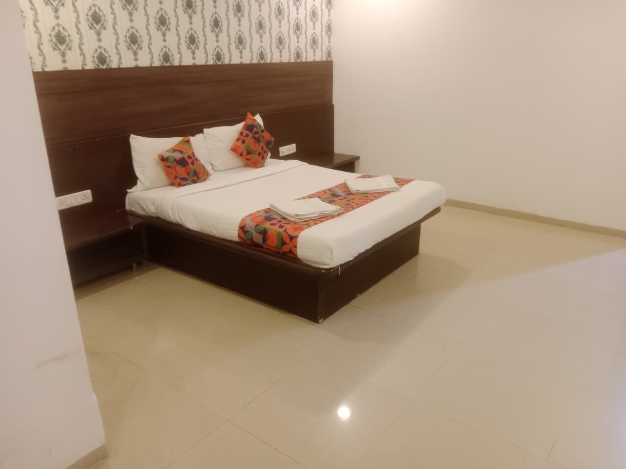 Una cama bien hecha con cabecera de madera, una mesita de noche y una pared con diseño.