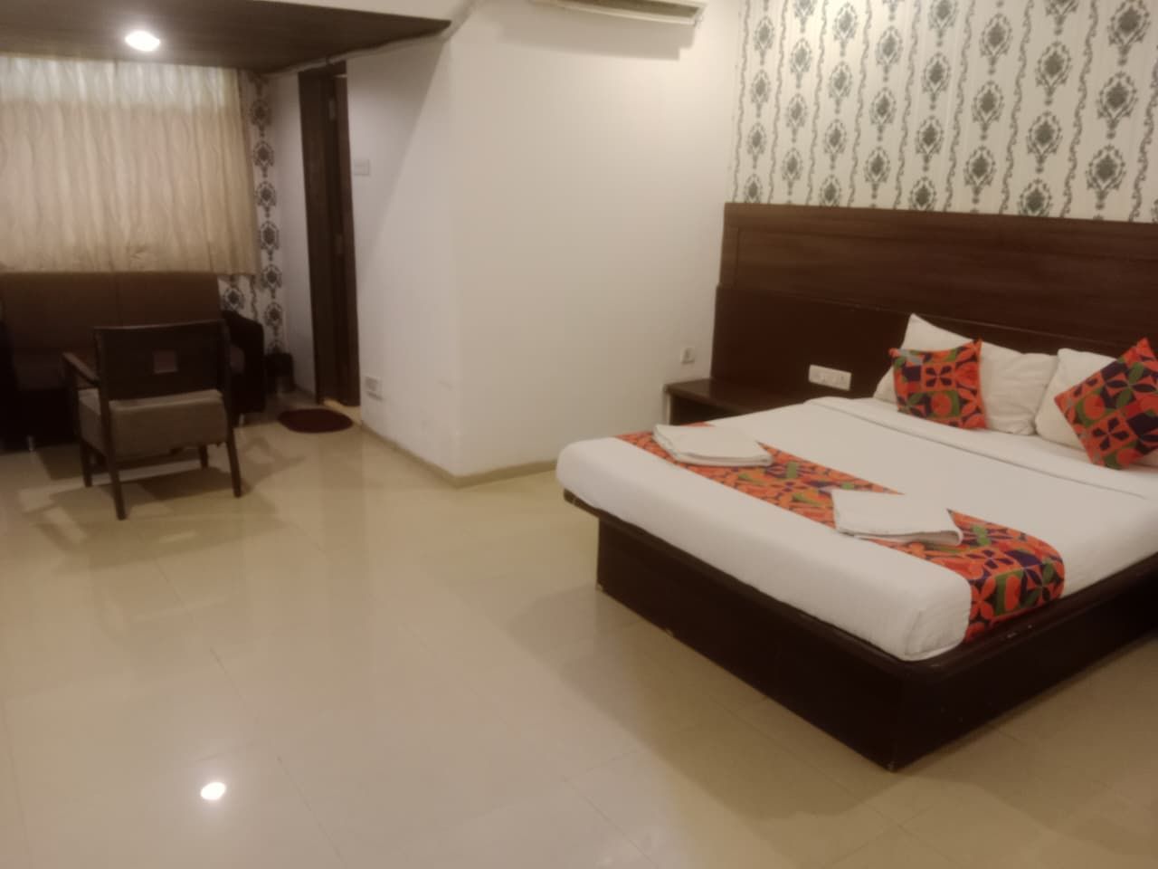 Una habitación de hotel con una cama, mesita de noche y una silla.