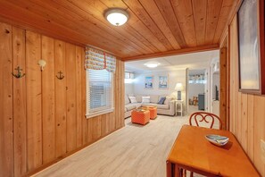 A wooden-paneled room with a dining table, a sofa, and a window with blinds. - JL #153 Rightmyer - Classic Oceanfront (Kill Devil Hills)