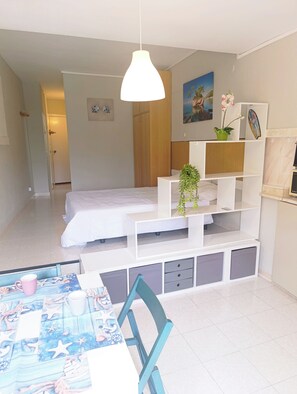 Ein Schlafzimmer mit einem Bett, einem weißen Schreibtisch, einem Stuhl und einer Pendelleuchte.