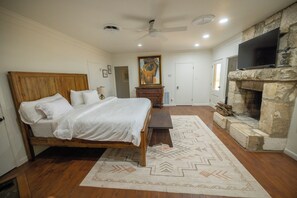 A bedroom with a wooden bed, a stone fireplace, and a television.