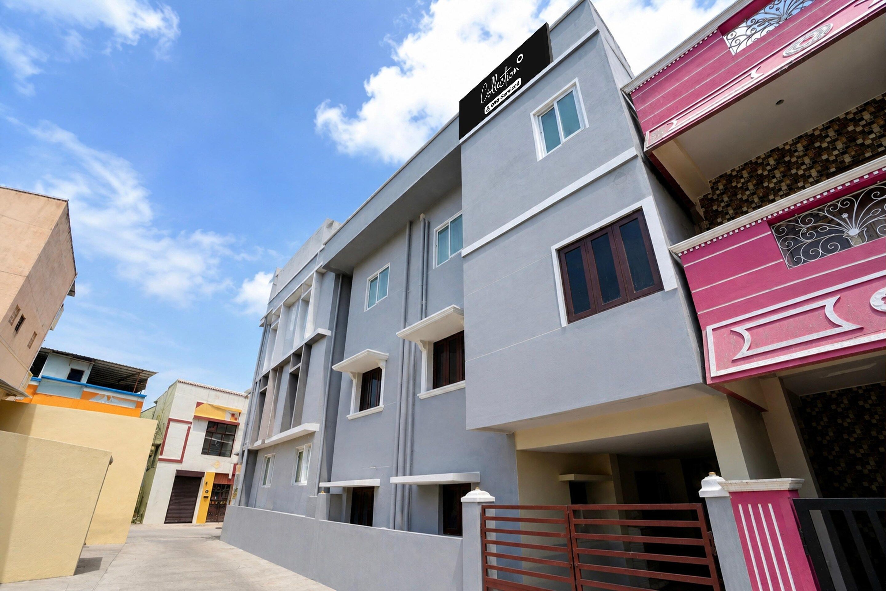 A multi-story residential building with a flat facade, a gated entrance, and a clear sky.
