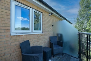 A balcony with two wicker chairs, a window, and a metal railing. - Heathrow Living 2BDR 2BA Apt 06-360stays (Stanwell)