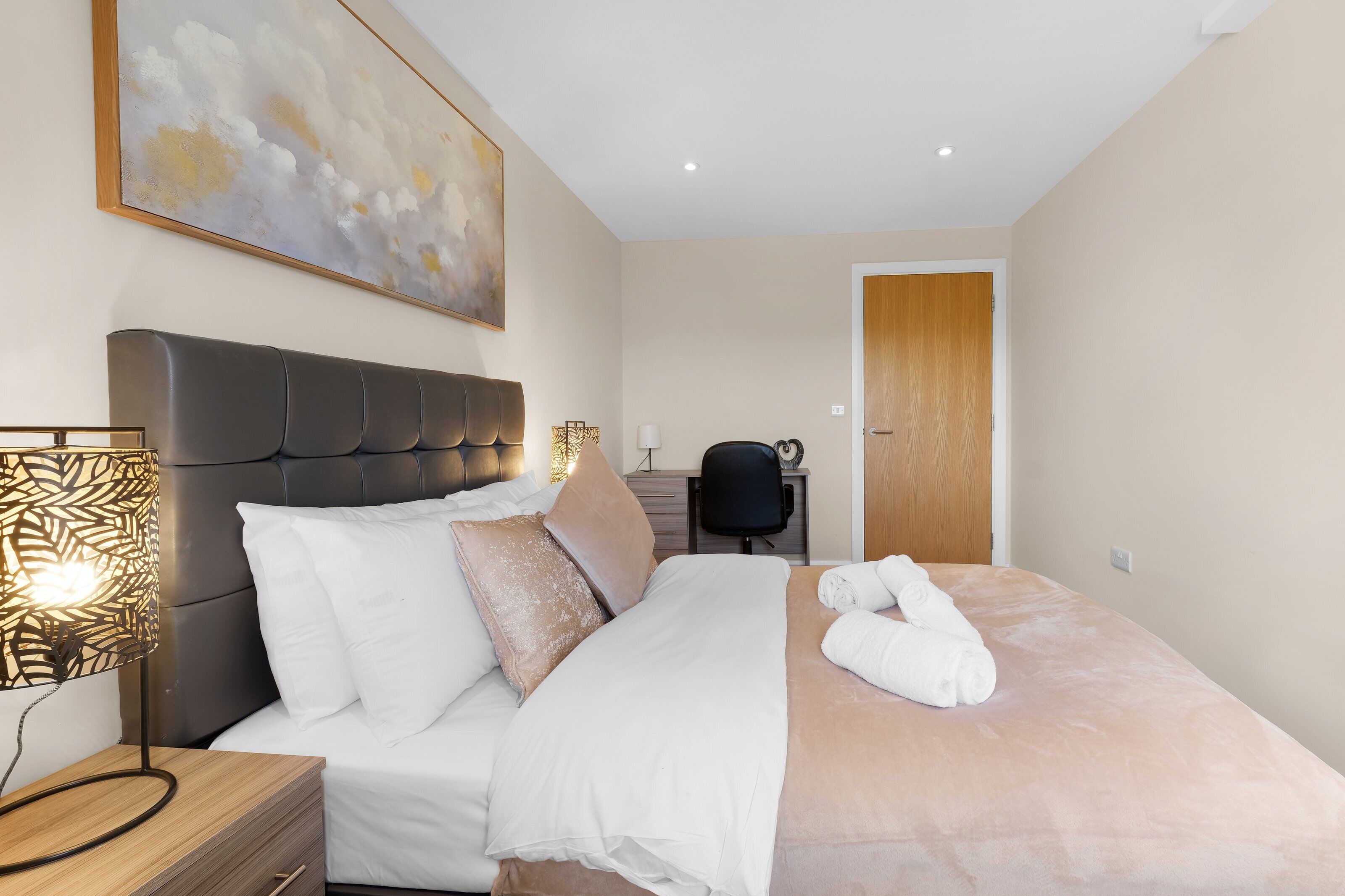 Una habitación de hotel con una cama, un escritorio, una silla y un cuadro en la pared.