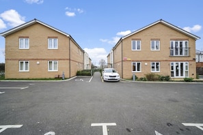 A residential street with two brick houses, a car parked in the middle, and a clear sky. - Heathrow Living 2BDR 2BA Apt 06-360stays (Stanwell)