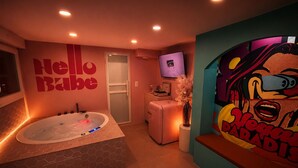 Ein modernes Badezimmer mit einer großen Badewanne, einer Dusche und einem WC. Ein wandmontierter Fernseher und ein dekoratives Gemälde sind vorhanden.