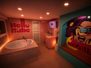 Ein modernes Badezimmer mit einer großen Badewanne, einer Dusche und einem WC. Ein wandmontierter Fernseher und ein dekoratives Gemälde sind vorhanden.