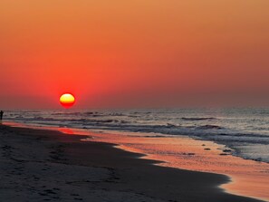 A beach at sunset with waves and a person walking. - Remodel Condo overlooks Pool walk to Celebration Park Beach & Coligny! (Hilton Head Island)