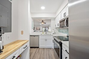 Una cocina moderna con armarios blancos, un refrigerador de acero inoxidable y un microondas integrado.