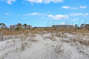 Ett hotell vid stranden med flera byggnader, en sandstrand och högt gräs.