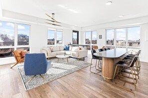 Ein geräumiges Wohnzimmer mit einer großen Couch, einem Couchtisch und einem Essbereich mit einem runden Tisch und Stühlen.