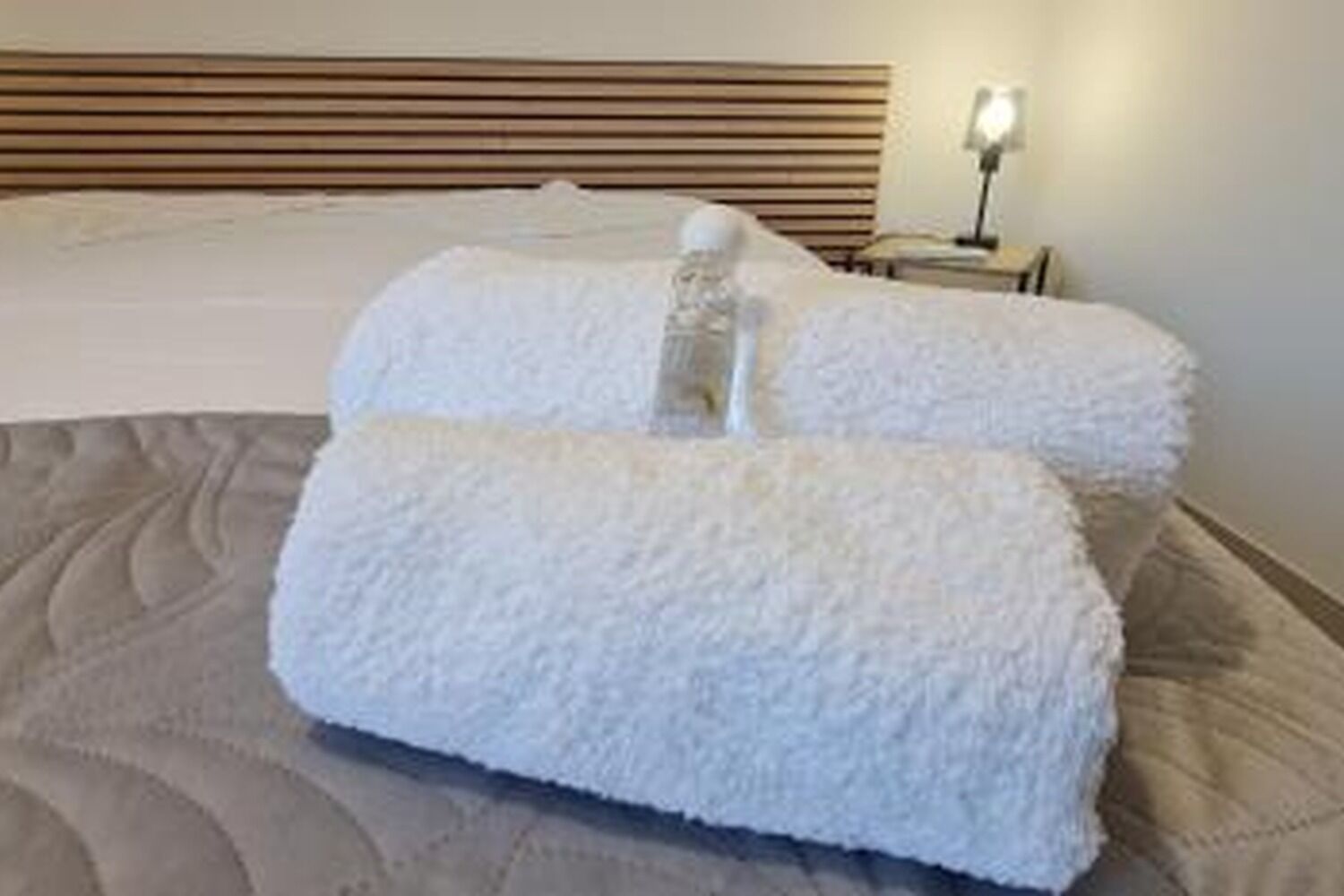 Een bed met witte kussens en een lamp op een nachtkastje.