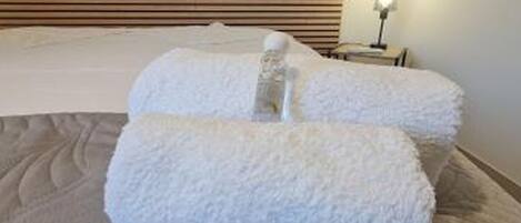 Een bed met witte kussens en een lamp op een nachtkastje.