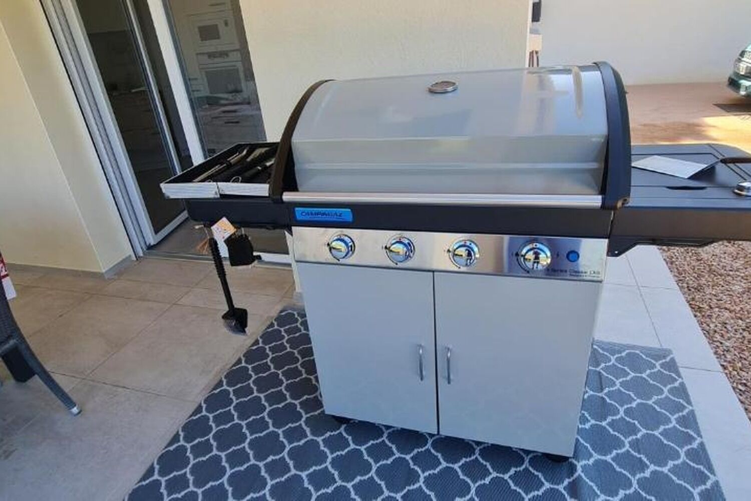An outdoor grill with four burners, a side burner, and a lid.