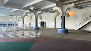 An indoor space with a checkered floor, large columns, and hanging spherical objects.