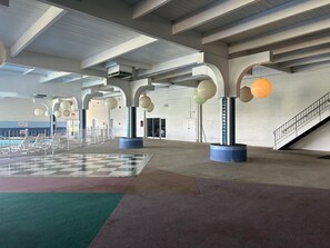 An indoor space with a checkered floor, large columns, and hanging spherical objects.