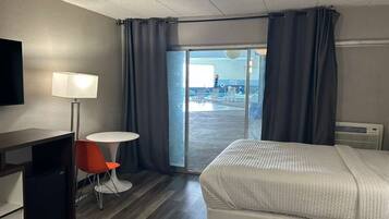 Une chambre d’hôtel avec deux lits, un bureau, une chaise, une télévision et une vue sur la piscine.