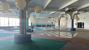 An indoor swimming pool area with multiple lanes, a checkered floor, and hanging spherical light fixtures.