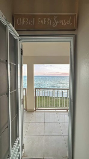 An open door leading to a balcony with a view of the sea and a sign above that reads 'CHERISH EVERY Sunset.' - Entire beachfront villa in Salinas, Puerto Rico (Salinas)