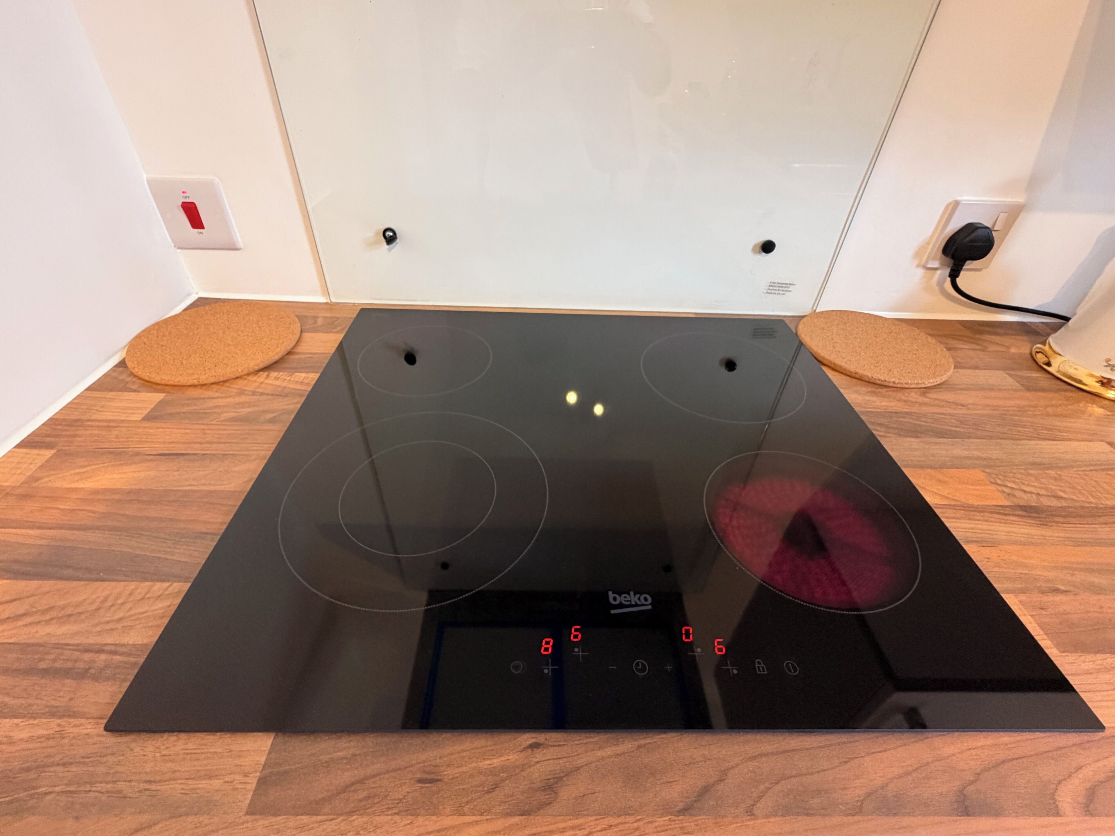 Un piano cottura a induzione nero con pannello di controllo digitale, due manopole e un cavo di alimentazione inserito.