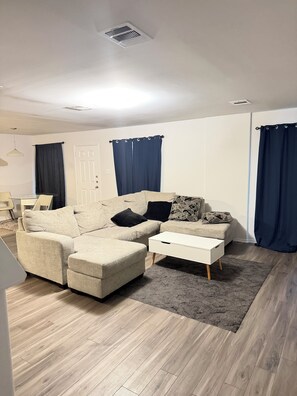A living room with a sectional sofa, a coffee table, and a rug. -  A Peaceful Richmond Stay in Houston Made for Comfort & Memories. (Richmond)