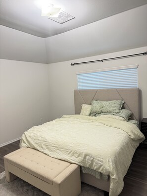 A bedroom with a bed, a bench, a window with blinds, and a ceiling light. -  A Peaceful Richmond Stay in Houston Made for Comfort & Memories. (Richmond)