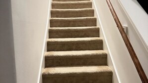 A carpeted staircase with a wooden handrail, leading to a white door at the top. -  A Peaceful Richmond Stay in Houston Made for Comfort & Memories. (Richmond)