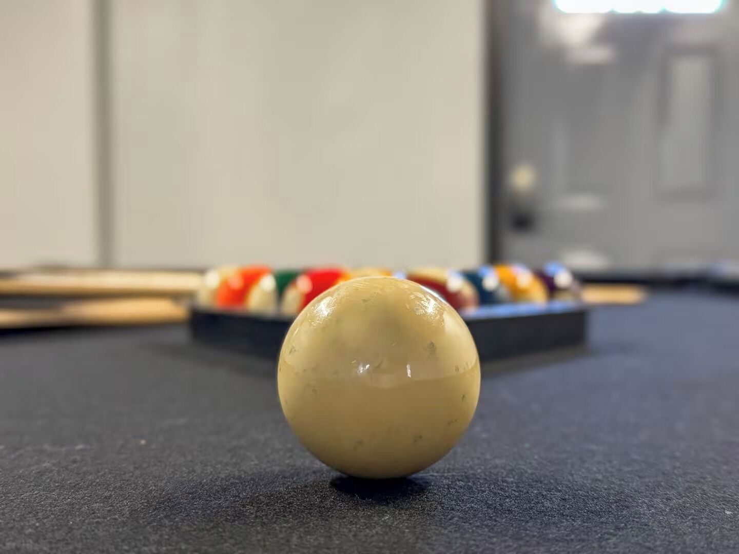 Een pooltafel met een witte knuppelbal op de voorgrond en een set streepballen op de achtergrond.