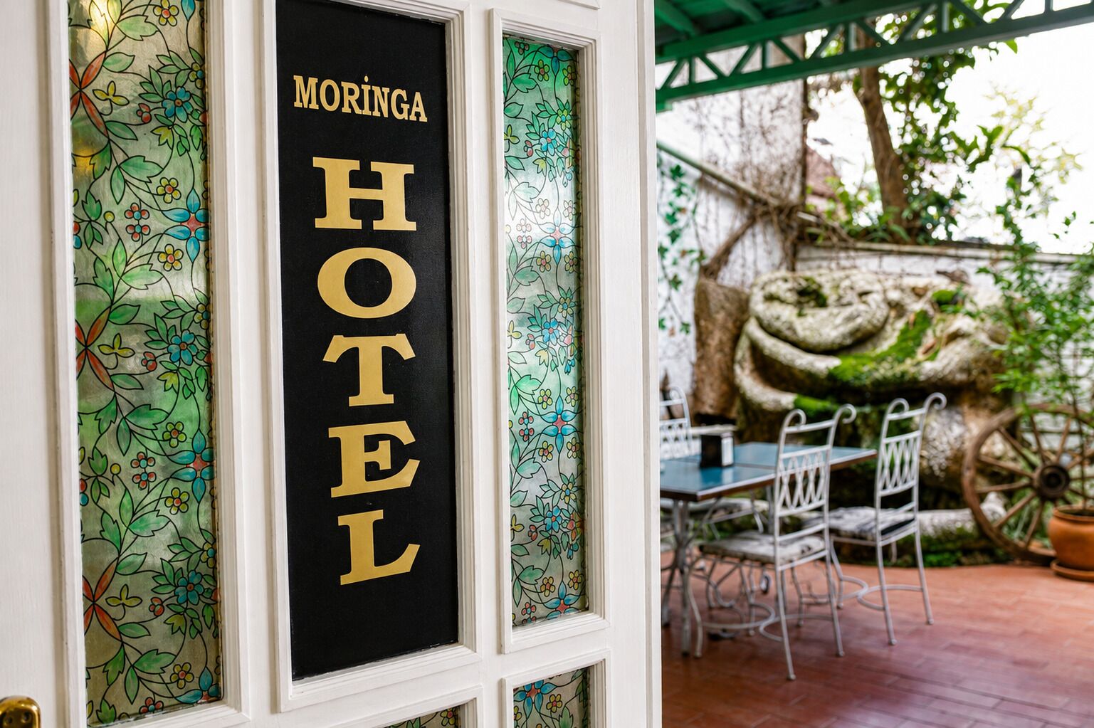 Letrero de hotel con 'MORINGA HOTEL' escrito en dorado sobre fondo negro.