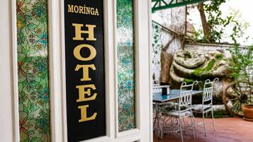 Letrero de hotel con 'MORINGA HOTEL' escrito en dorado sobre fondo negro.