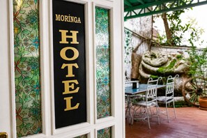 Une enseigne d’hôtel avec l’inscription « MORINGA HOTEL » en lettres dorées sur un fond noir.
