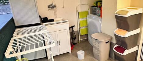 A compact kitchenette with a white countertop, a small sink, and a trash bin.