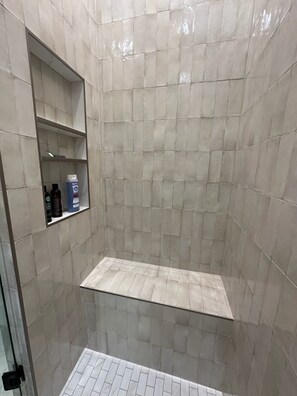 A shower area with tiled walls and a shelf with toiletries. - Escape to this stylist 3-bedroom 2-bath mountain retreat in charming Cashiers. (Cashiers)