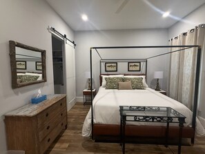Un lit à baldaquin, une commode avec un miroir et une table de chevet avec une lampe.