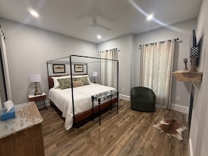 A four-poster bed with a wooden frame, a bedside table with a lamp, a chair, and a small table with a tissue box. - Escape to this stylist 3-bedroom 2-bath mountain retreat in charming Cashiers. (Cashiers)