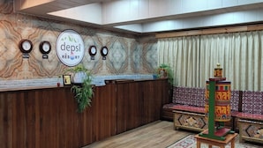 A reception area with a wooden reception desk, a clock, and a sign that reads 'depsi RÉSORT'.