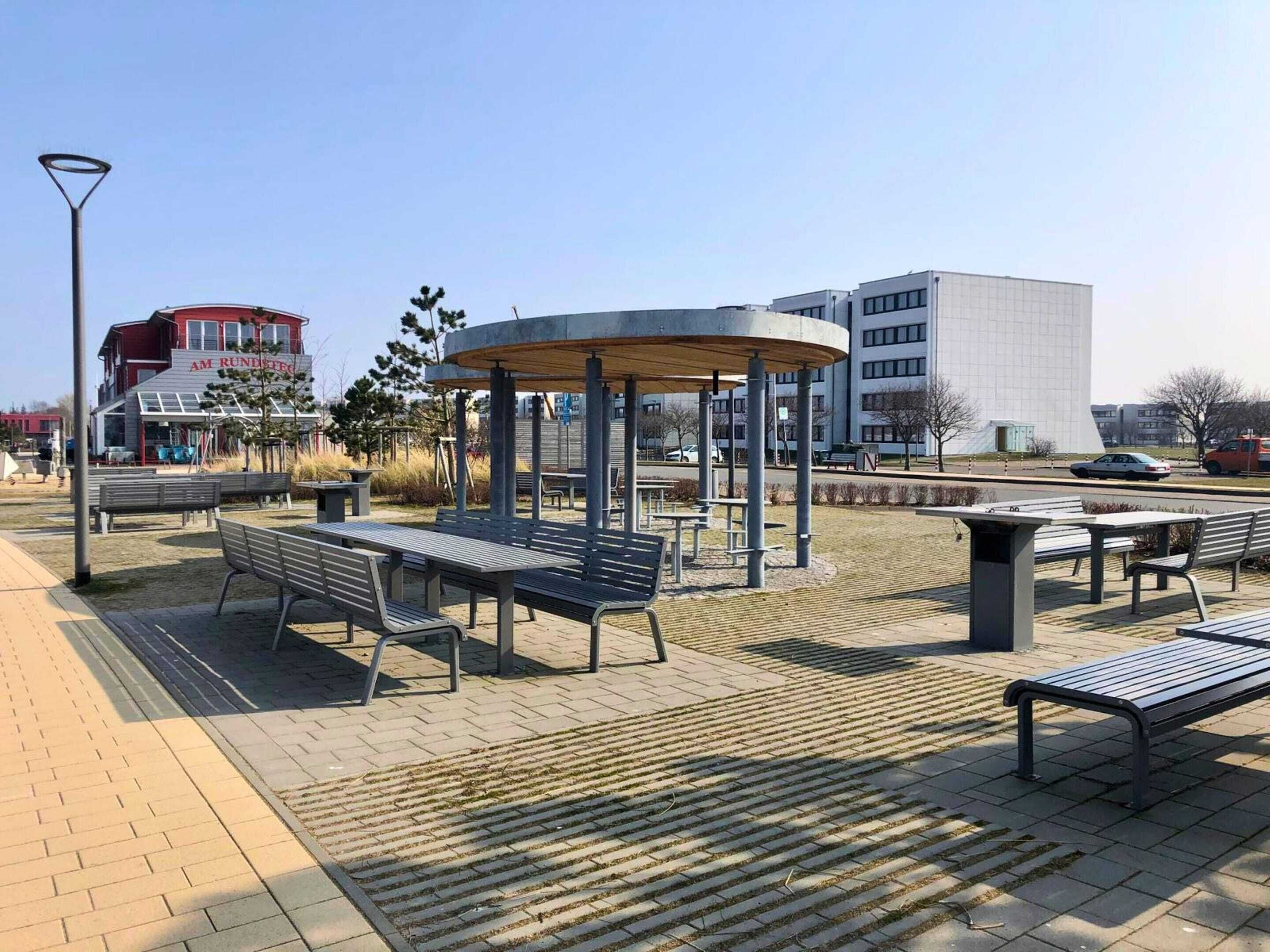 A park with benches, a gazebo, and a building in the background.