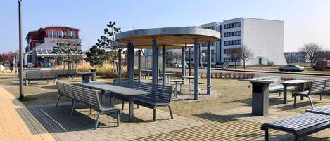 A park with benches, a gazebo, and a building in the background.
