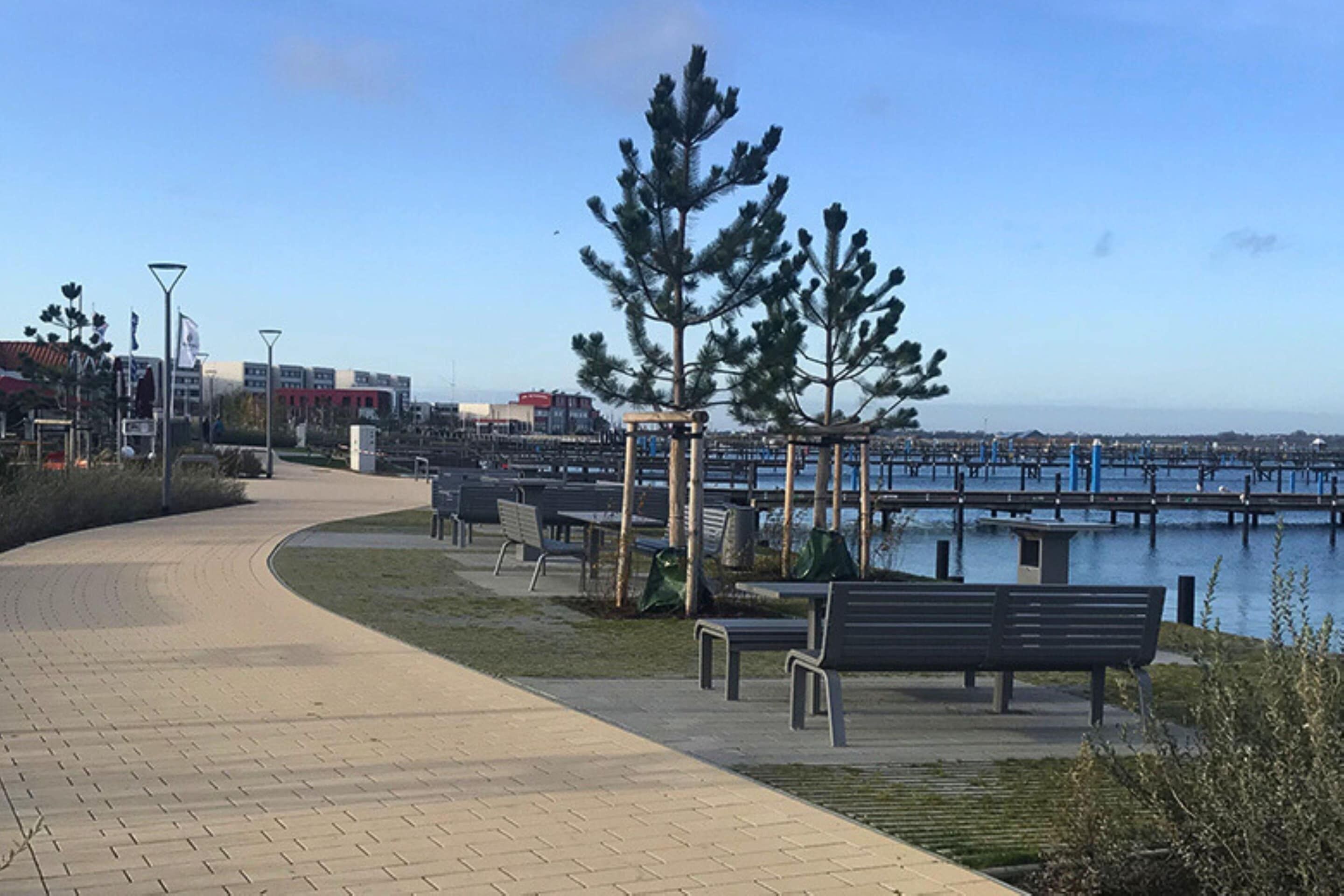 A paved walkway with benches and a gazebo overlooking a body of water.