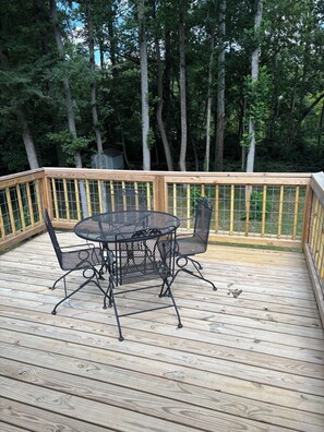 Eine Holzterrasse mit einem runden Tisch und Stühlen, umgeben von einer Holzbrüstung.